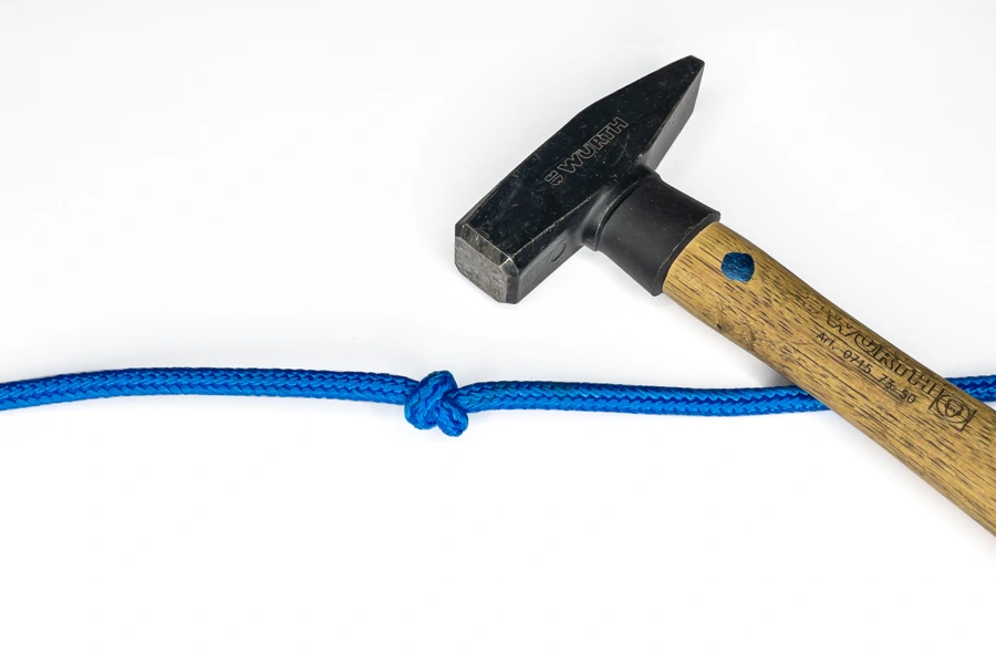 Bei einem Seil den Knoten mit einem Hammer lockern.