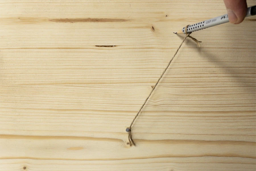 Eine Schnur wird als Abstandsbegrenzer zwischen Nagel und Stift befestigt.